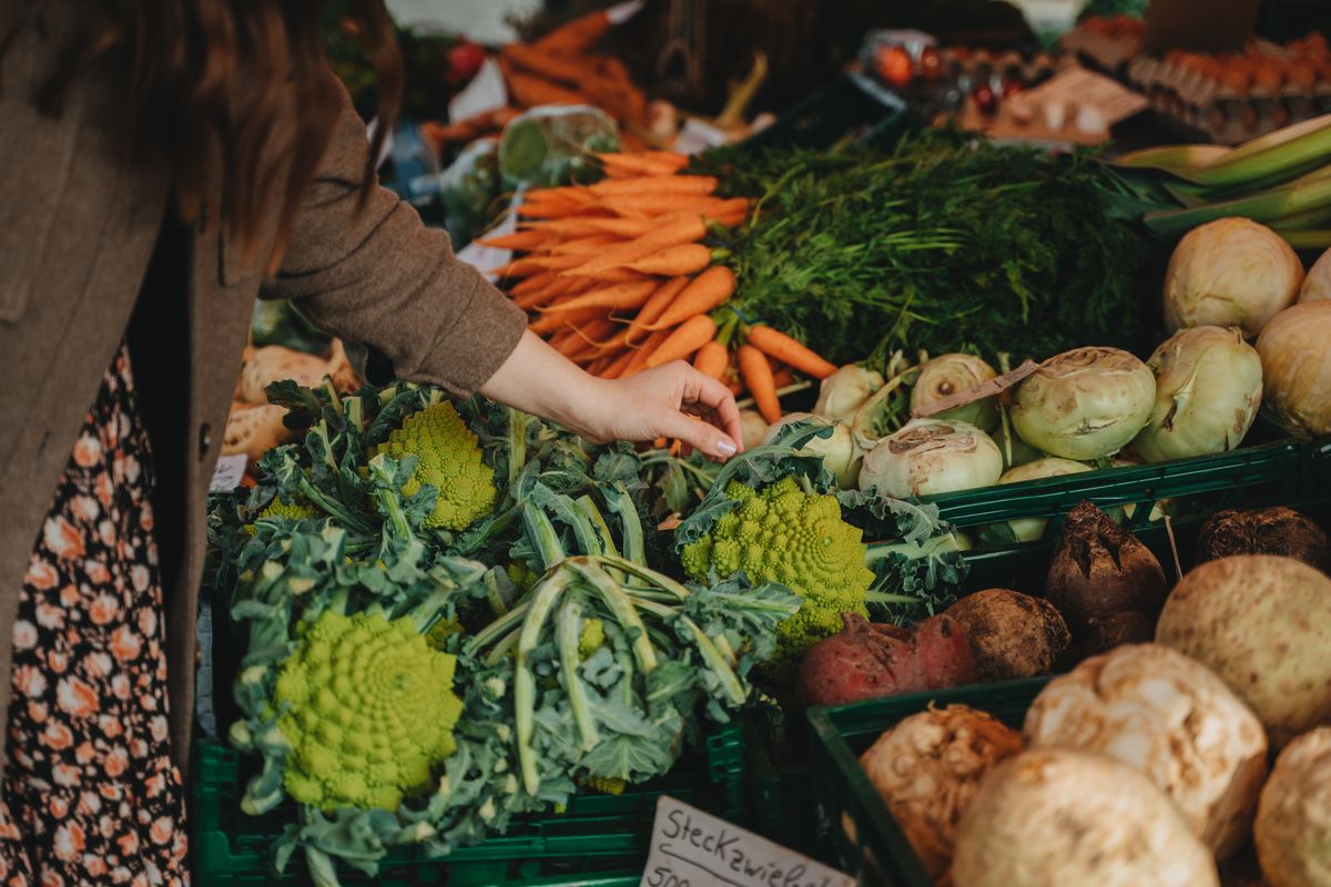 A shopper selecting fresh vegetables at a local market